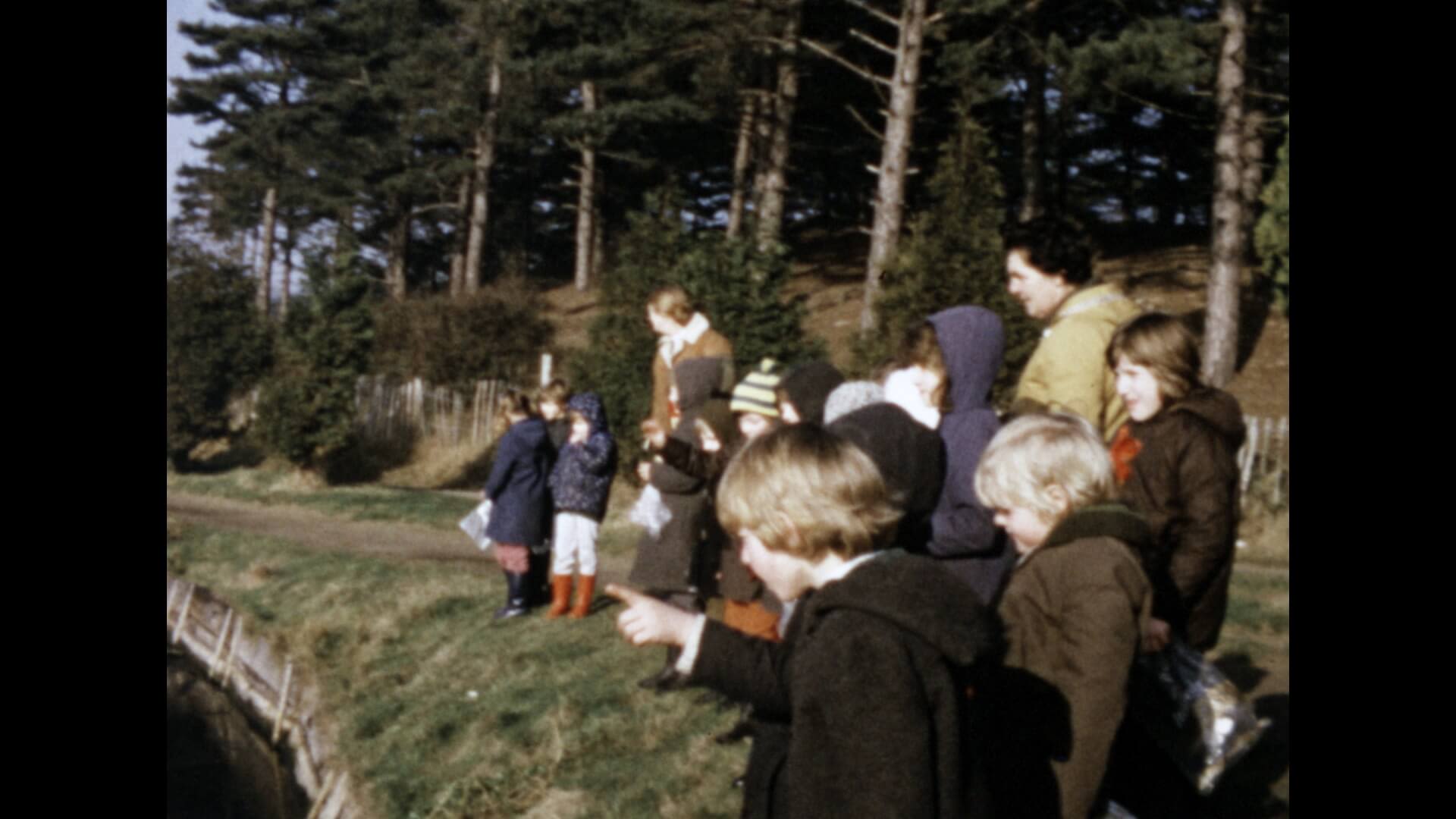 a group of children and adults standing in front of a forest