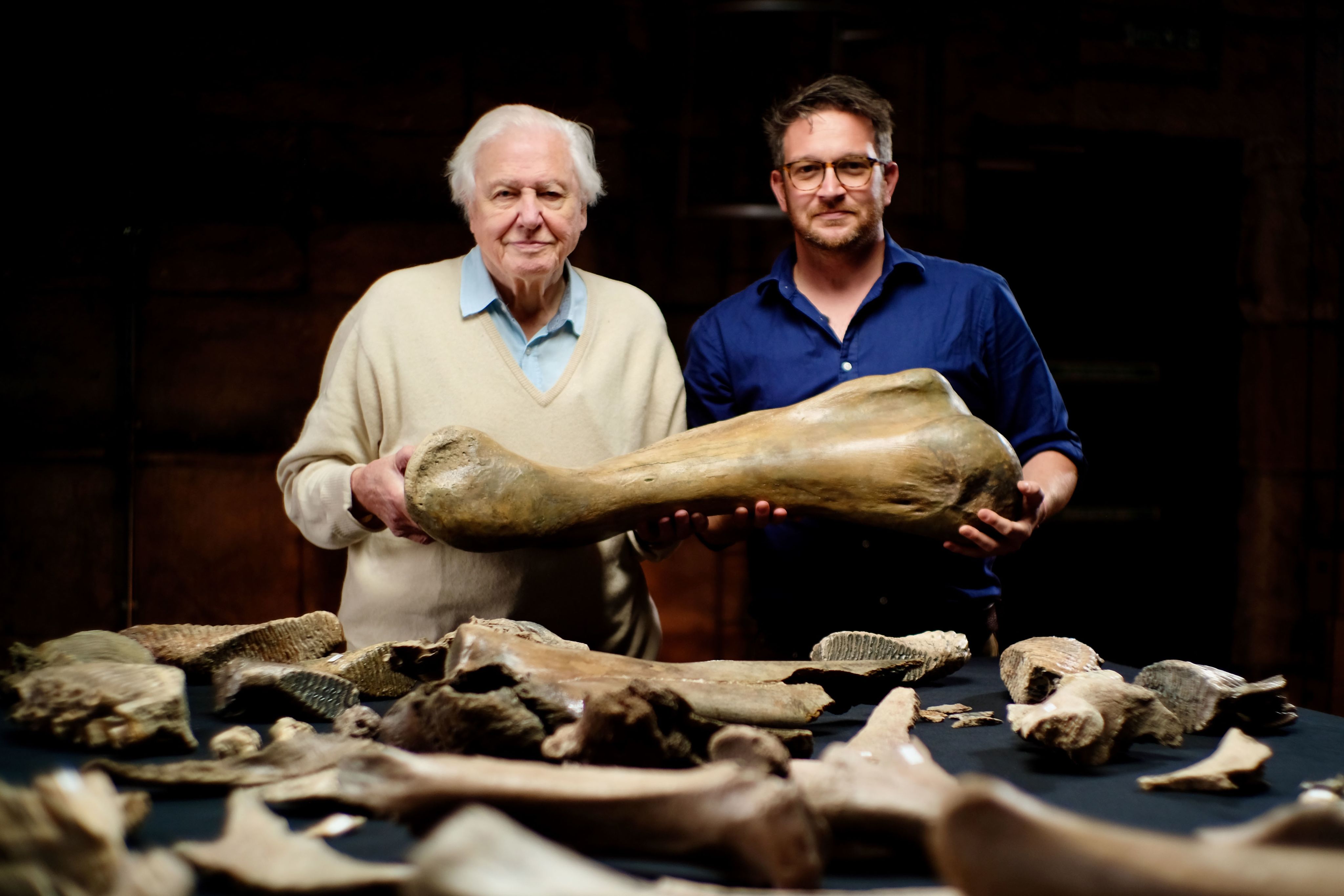 two people holding looking toward the camera and holding a large bone
