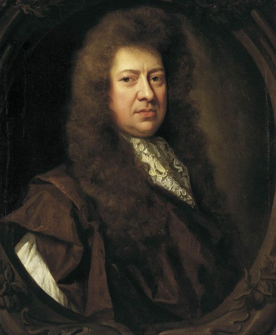 A man in a wig and fancy clothes sits at a desk