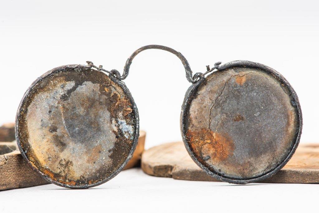 A pair of intact but battered spectacles with an open case behind them