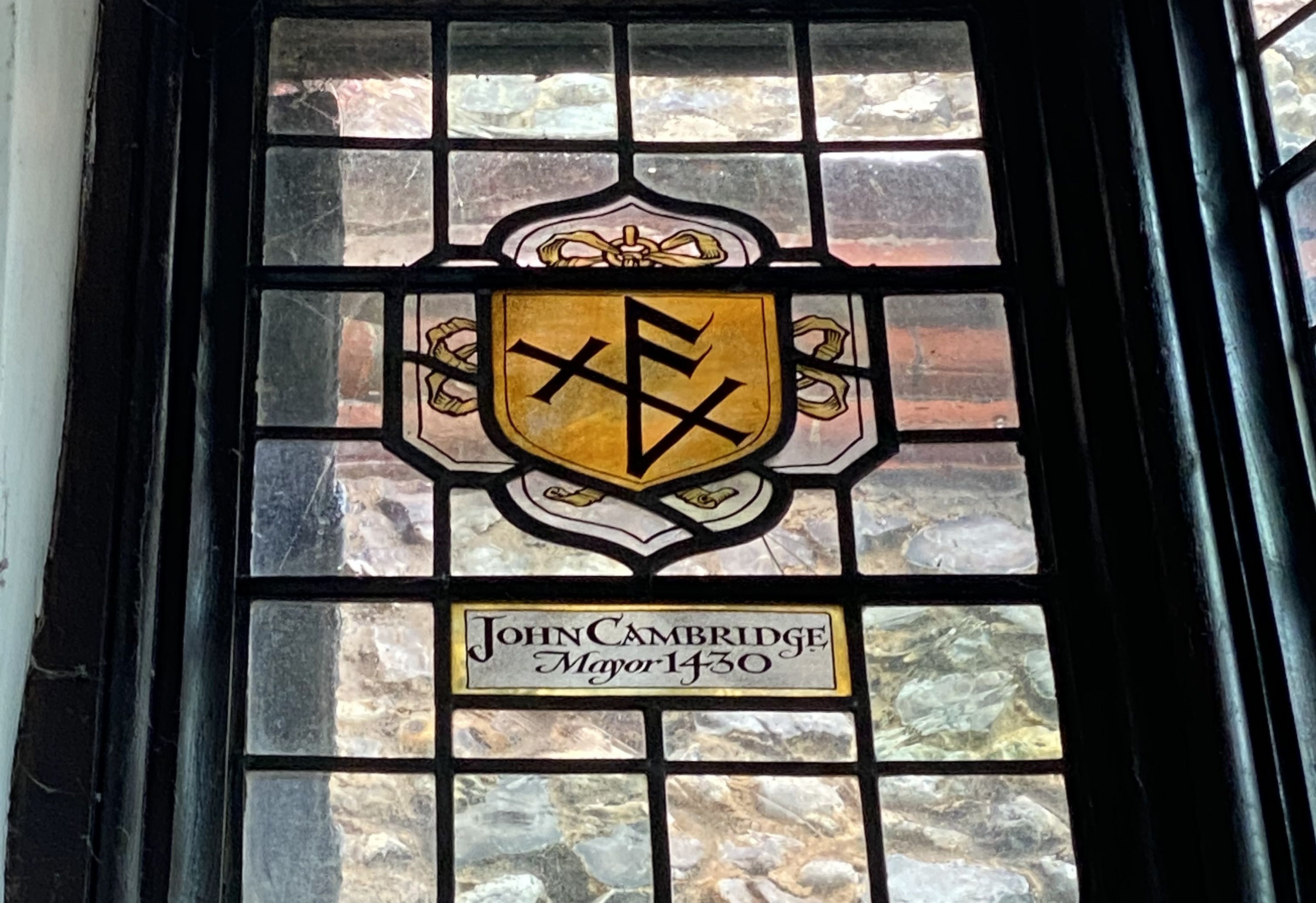 A merchants' mark rendered in a stained glass panel.