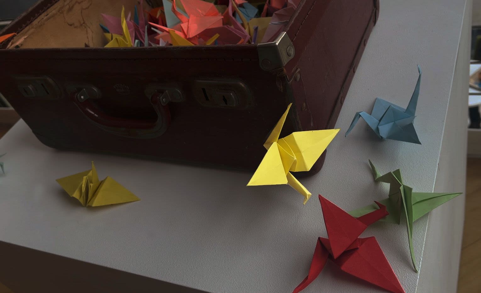 Origami birds filling and flying out from a battered suitcase