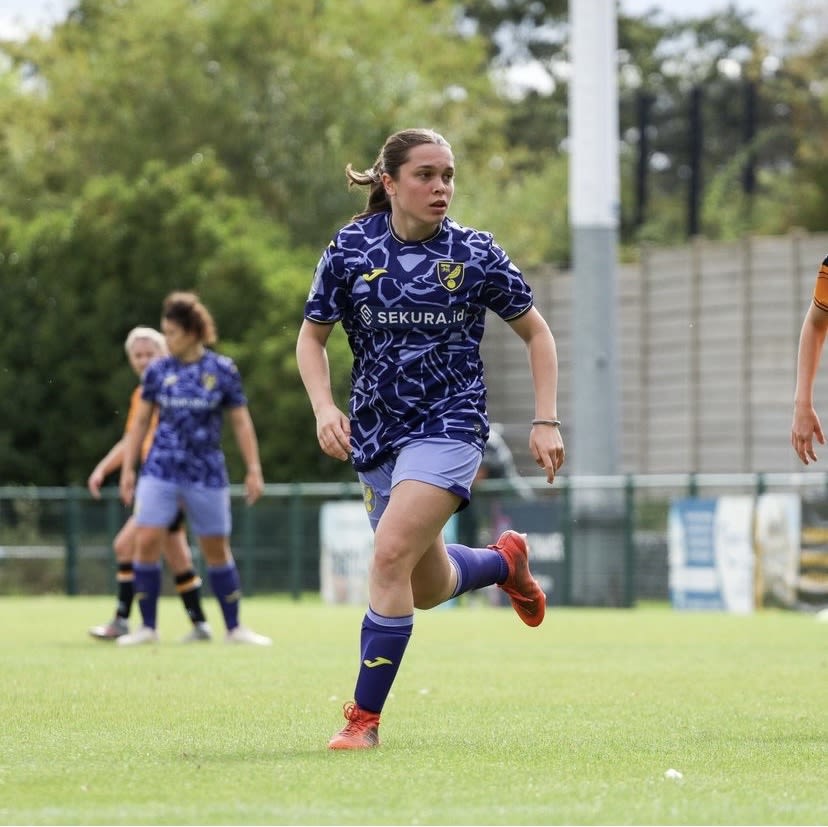 Rachel Lawrence running on a football pitch, wearing purple football uniform
