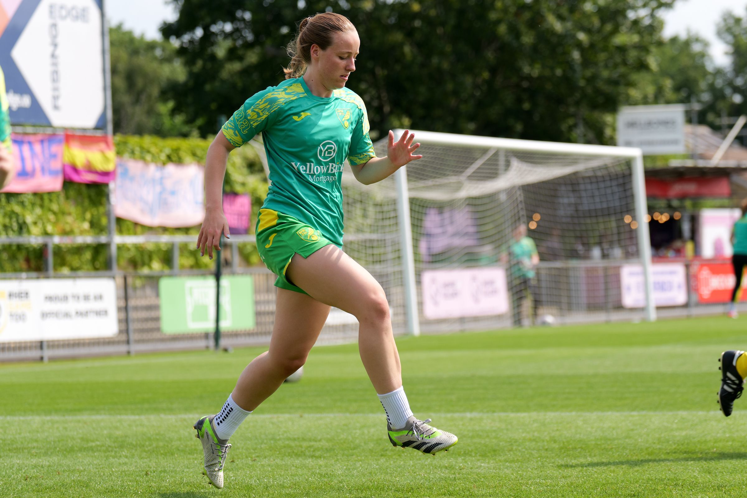 Millie Daviss warming up on the pitch in her green and yellow Norwich City kit