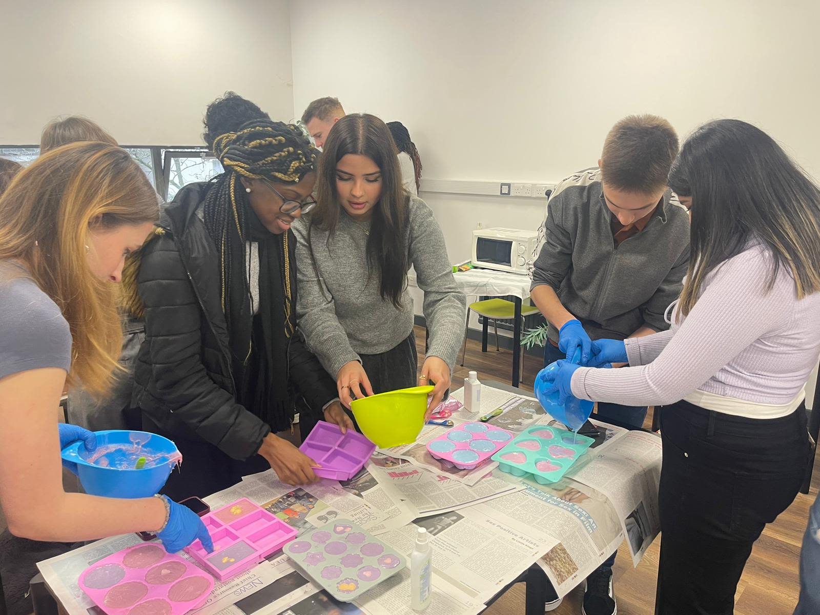 A group of students adding handmade soap to moulds at a soap-making workshop