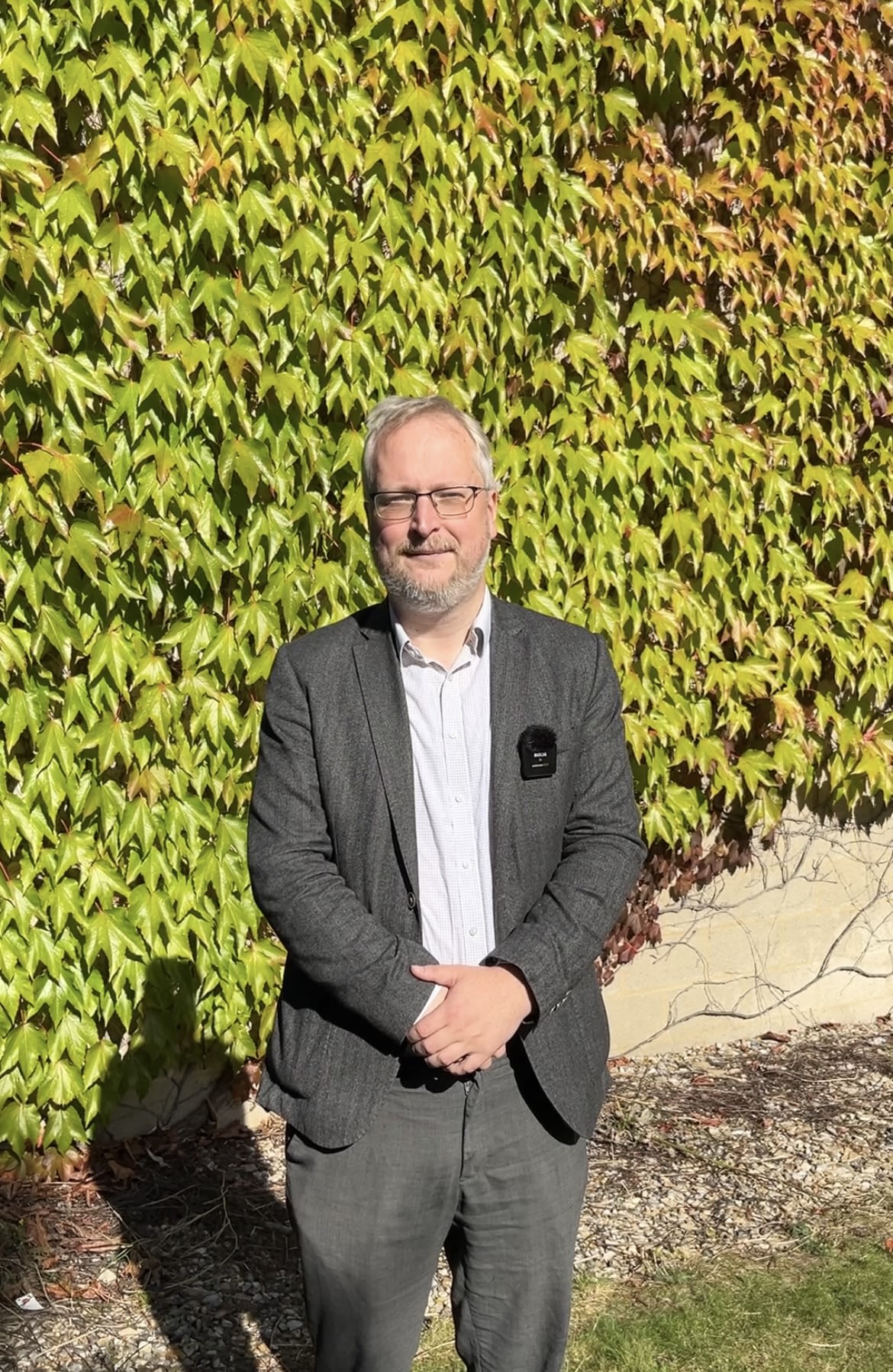 Tom Roebuck standing in front of a wall of green leaves